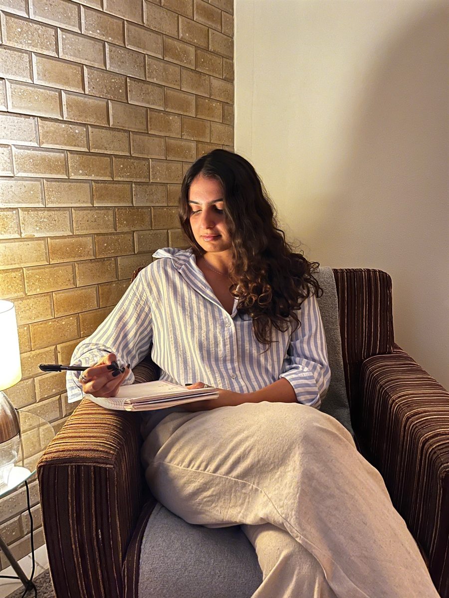 Ana Laís Teixeira sentada na poltrona do consultório, anotando em um caderno
